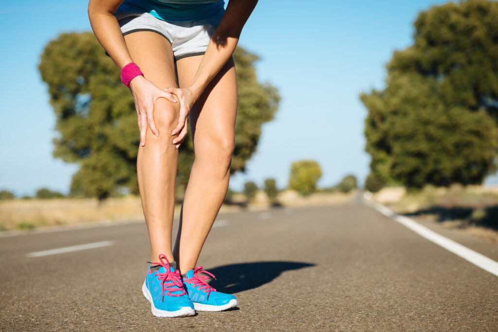 En person der løber på en vej, som har ondt i sin højre knæ - Knæsmerter