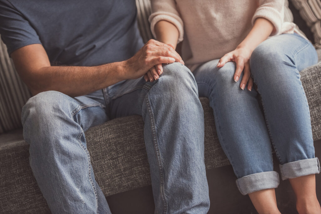 Et par der sidder i en sofa der holder hænder og er nervøse - Kvinde - og mande problemer